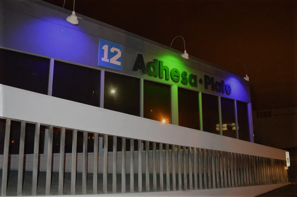 The Adhesa Plate building lit in blue and green at night